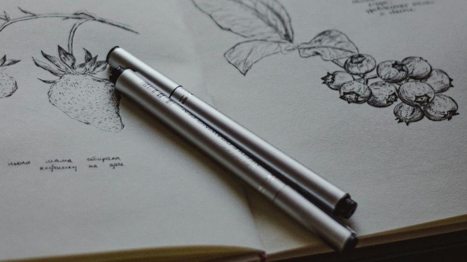Penne appoggiate su uno sketchbook disegnato